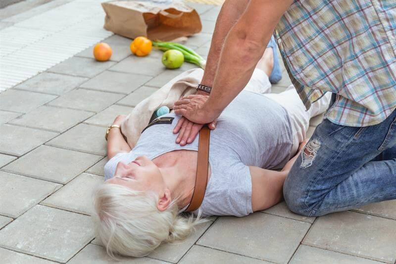 Man performs a heart massage on an senior lady who collapse on the street.